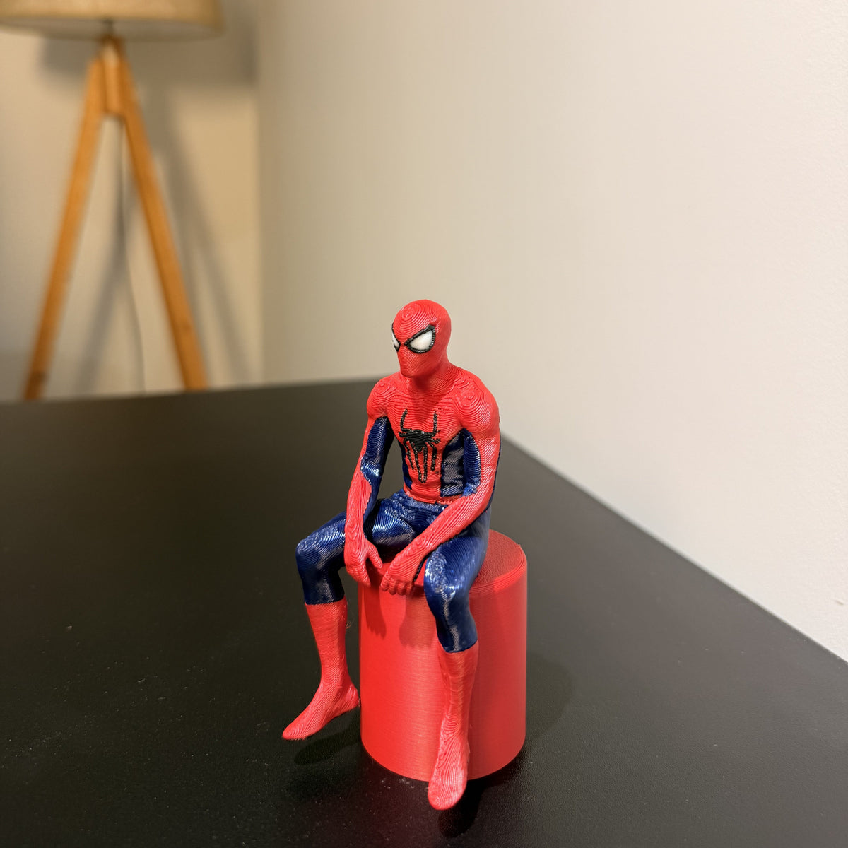 Sitting Spider-Man figurine on red display pedestal