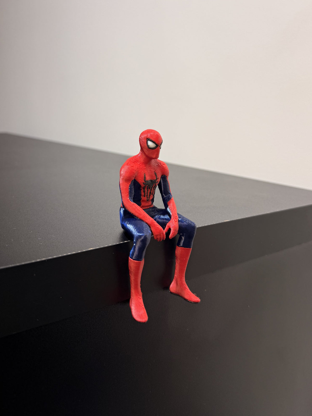Sitting Spider-Man figurine perched on shelf edge